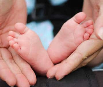 A parent holds their newborns tiny feet